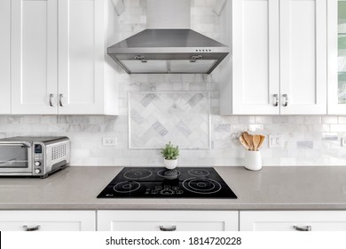 ELMHURST, IL, USA - AUGUST 4, 2020: Detail shot of a white luxurious kitchen stove and hood. A marble custom tile back splash is under the white cabinets.