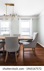 ELMHURST, IL, USA - FEBRUARY 2, 2020: A Beautiful Dining Room Detail Shot With Light Green Walls, A Gold Light Fixture, And Wood Tables And Chairs.