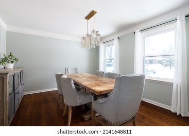 ELMHURST, IL, USA - FEBRUARY 2, 2020: A Beautiful Dining Room Detail Shot With Light Green Walls, A Gold Light Fixture, And Wood Tables And Chairs.