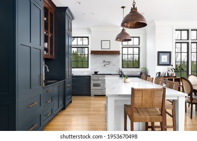 ELMHURST, IL, USA - FEBRUARY 24, 2021: A Luxurious Kitchen With Blue Cabinets, Bronze Dome Light Fixtures Hanging Above The Large White Island, And Luxury Appliances.