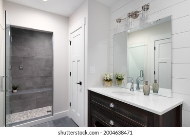 ELMHURST, IL, USA - JANUARY 22, 2021: A Beautiful Bathroom With A Shiplap Wall, Dark Wood Vanity Cabinet, And A Marble Countertop. The Shower Is Tiled With A Glass Door.