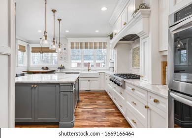 ELMHURST, IL, USA - JANUARY 30, 2020: A luxurious, white kitchen with a granite counter top and a tiled backsplash behind the stainless steel KitchenAid stovetop.