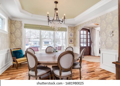 ELMHURST, IL, USA - JANUARY 30, 2020: A Luxurious Dining Room With A Large Table That Sits Six People. A Fancy Chandelier Hangs From The Raised, Light Green Ceiling With Beautiful Hardwood Floors.