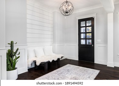 ELMHURST, IL, USA - NOVEMBER 1, 2020:  A Beautiful Foyer Entrance With A Light Hanging Above The Dark Hardwood Floors, A Bench In Front Of A Shiplap Wall, And A Dark Door With Windows.