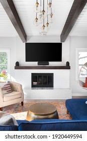 ELMHURST, IL, USA - SEPTEMBER 2, 2020: A Renovated Modern Farmhouse Living Room With A Blue Couch, White Fireplace, Wood Beams On A White Shiplap Ceiling, And A Television Mounted Above The Fireplace.