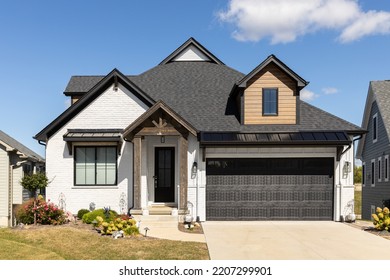 ELMHURST, IL, USA - SEPTEMBER 25, 2022: A Beautiful, Modern Farmhouse Home With A White Brick And Wood Siding, Black Roof, And Wooden Pillars.