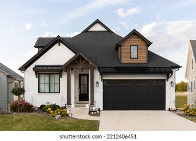 ELMHURST, IL, USA - SEPTEMBER 25, 2022: A Beautiful, Modern Farmhouse Home With A White Brick And Wood Siding, Black Roof, And Wooden Pillars.