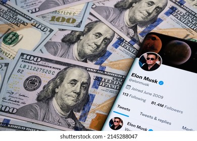 Elon Musk's Twitter account page on the smartphone which is is placed on the pile of dollar banknotes. Twitter cash takeover concept. Stafford, United Kingdom, April 11, 2022