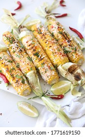 Elotes, Grilled Mexican Street Corn, Summer, BBQ , Fast, Healthy Food Concept, Top View, Flat Lay, White Background, Decorated With Red Hot Chili Peppers Lime And Cilantro Leaves