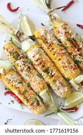 Elotes, Grilled Mexican Street Corn, Summer, BBQ , Fast, Healthy Food Concept, Top View, Flat Lay, White Background, Decorated With Red Hot Chili Peppers Lime And Cilantro Leaves