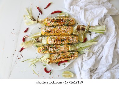 Elotes, Grilled Mexican Street Corn, Summer, BBQ , Fast, Healthy Food Concept, Top View, Flat Lay, White Background, Decorated With Red Hot Chili Peppers Lime And Cilantro Leaves