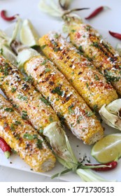 Elotes, Grilled Mexican Street Corn, Summer, BBQ , Fast, Healthy Food Concept, Top View, Flat Lay, White Background, Decorated With Red Hot Chili Peppers Lime And Cilantro Leaves