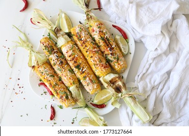 Elotes, Grilled Mexican Street Corn, Summer, BBQ , Fast, Healthy Food Concept, Top View, Flat Lay, White Background, Decorated With Red Hot Chili Peppers Lime And Cilantro Leaves