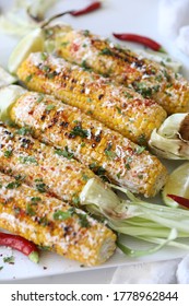 Elotes, Grilled Mexican Street Corn, Summer, BBQ , Fast, Healthy Food Concept, Top View, Flat Lay, White Background, Decorated With Red Hot Chili Peppers Lime And Cilantro Leaves