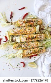 Elotes, Grilled Mexican Street Corn, Summer, BBQ , Fast, Healthy Food Concept, Top View, Flat Lay, White Background, Decorated With Red Hot Chili Peppers Lime And Cilantro Leaves