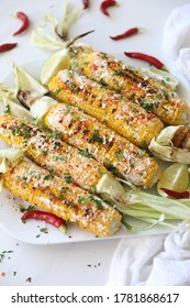 Elotes, Grilled Mexican Street Corn, Summer, BBQ , Fast, Healthy Food Concept, Top View, Flat Lay, White Background, Decorated With Red Hot Chili Peppers Lime And Cilantro Leaves