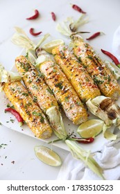 Elotes, Grilled Mexican Street Corn, Summer, BBQ , Fast, Healthy Food Concept, Top View, Flat Lay, White Background, Decorated With Red Hot Chili Peppers Lime And Cilantro Leaves