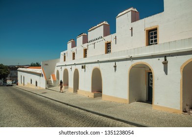 Elvas, Portugal - July 7, 2018. Little Girl Walking On Sidewalk Next To Whitewashed Building With Arches In Elvas. A Gracious Star-shaped Fortress City On The Easternmost Frontier Of Portugal.