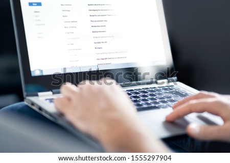 Email inbox full of messages and text. Man reading electronic mail with laptop. Spam, junk and e marketing on screen. Looking and checking received posts. Busy entrepreneur working and using computer.