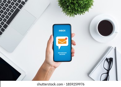 Email marketing and newsletter concept. Top view of unrecognizable young woman holding modern mobile phone with new mail notification on screen, creative collage