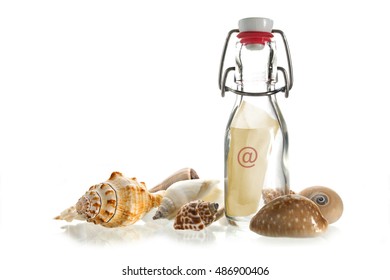 Email Message In A Bottle Made Of Glass Between Some Sea Shells Isolated On A White Background