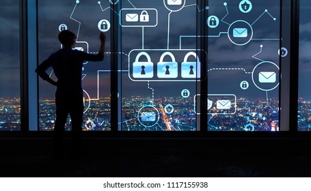 Email security theme with man writing on large windows high above a sprawling city at night - Powered by Shutterstock