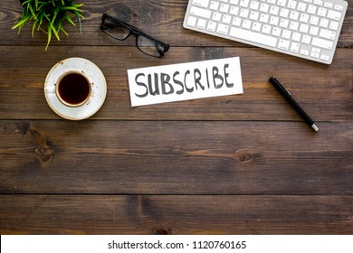 Email subscribe concept. Hand lettering subcribe on work desk with plant, glasses, computer keyboard, cup of coffee on dark wooden background top view copy space - Shutterstock ID 1120760165