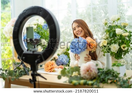eMarketer,Live Streaming,streamers,live selling industry and SME florist gift shop owner concept.Asia owner woman smile and Live Streaming on mobile application by mobile phone for sell flower at home