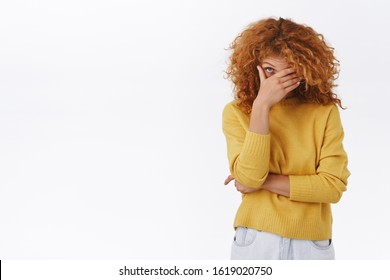 Embarrassed Attractive Modern Redhead Curly Girlfriend In Yellow Sweater Blushing As Boyfriend Behaving Dumb In Front Of Her Friends, Making Facepalm And Peek With One Eye At Awkward Situation