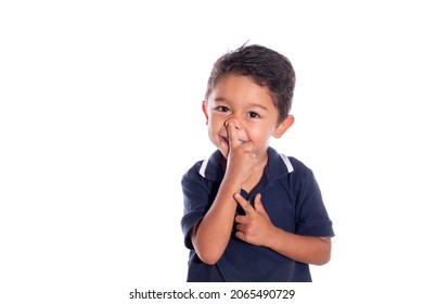 Embarrassed Boy Trying To Pick His Nose, Isolated On White Background. Latin Child Laughing While Touching Tip Of His Nose.