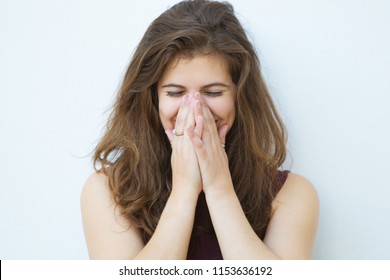 Embarrassed Girl Laughing And Covering Mouth With Hands. Pretty Young Woman With Brown Hair Keeping Eyes Closed And Smiling. Blushing Concept