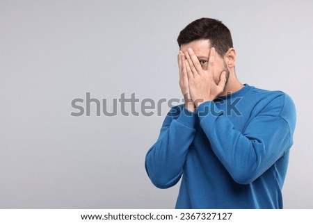Embarrassed man covering face on light grey background. Space for text