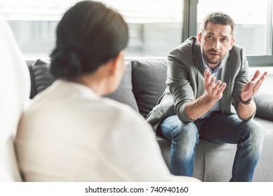 Embarrassed Man Speaking To Psychotherapist