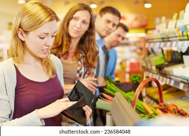 Embarrassed Woman Looking For Money In Her Wallet At Supermarket Checkout