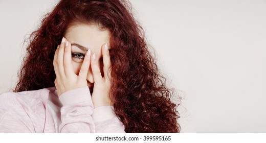 Embarrassed Young Woman Covering Face With Hands And Peeking Through Her Fingers