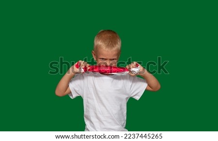 Embittered boy pulls paper with his hands, tries to tear it. Protest, fatigue, training, coercion, discontent, disobedience, upbringing, denial. Selective focus.