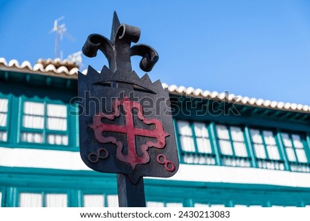 Emblem of the Order of Calatrava, red Greek cross with fleur-de-lis at its ends, in the Plaza Mayor of Almagro, Ciudad Real.Bokeh the background. sightseeing in Castilla La Mancha, Spain
