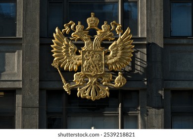 The emblem of the Russian Federation on the facade of the State Duma building. Luxurious golden coat of arms on the facade of the building