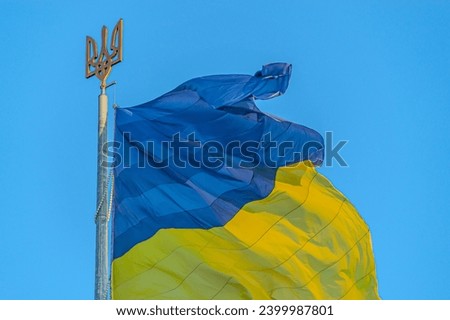 Emblem of Ukraine. Ukraine flag large national symbol fluttering in blue sky. Large yellow blue Ukrainian state flag. National flag of Ukraine against blue sky. Detail of the national flag of Ukraine