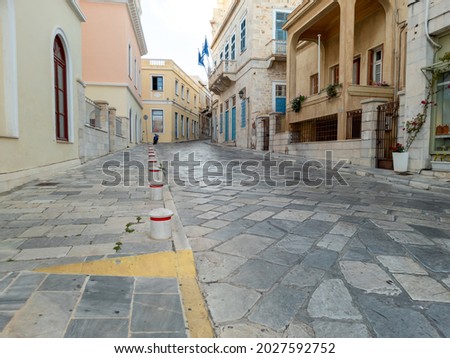 Emblematic traditional neoclassical buildings at capital of Siros Ermoupolis Syros island, Cyclades, Greece. Empty cobblestone streets pavements balconies summer day. Resort destination. Advertisement