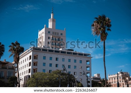 Emblematic white modernist building of the Soho Boutique Equitativa hotel in Malaga stands out against the vibrant blue sky in the background