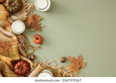 Embrace the beauty of autumn. Top view photo of candles, comfortable plaid, pumpkins, acorns, autumn leaves on pastel olive background with empty space for advert or text