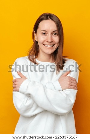Embrace equity concept in a vertical portrait of a wide smiling woman embracing herself.