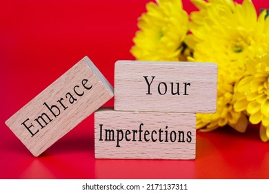 Embrace your imperfections text on wooden cube and with flowers bouquet background.
