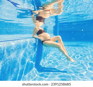 Embracing aquatic fitness, a pregnant woman demonstrates strength and serenity in underwater aerobics, creating a serene and empowering image in the pool - Powered by Shutterstock