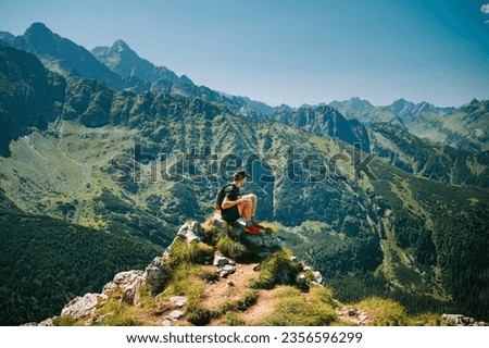 Embracing the beauty of the Belianske Tatras, a young traveler revels in serenity, all while the High Tatras' grandeur unfolds in the backdrop [[stock_photo]] © 