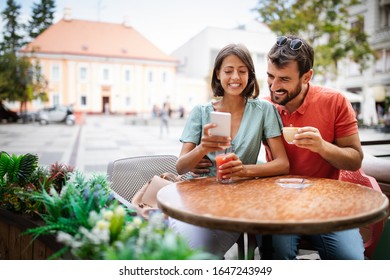 Embracing couple using mobile phone, smiling and talking in cafe - Powered by Shutterstock