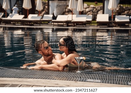 Embracing each other. Man with woman is in the pool together.