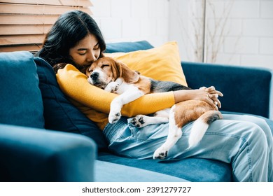 Embracing the essence of trust and love, a young Asian woman and her Beagle dog nap together on the sofa in their living room, highlighting their bond and togetherness. Pet love - Powered by Shutterstock