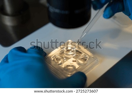 Embriologist putting sperm sample to examine under microscope or collecting in vitro cultured embryos for biopsy. Reproductive medicine clinic. Artificial insemination. Artificial conception clinic.